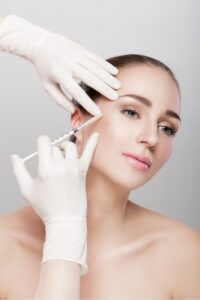 brunette female receiving BOTOX injection to her temples. BOTOX Salem, OR