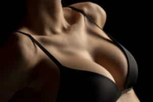 Woman with perfect breasts in black bra on black background